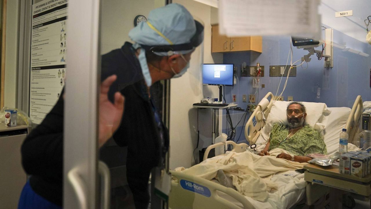 Registered nurse Kobie Walsh, left, checks on a COVID-19 patient at St. Joseph Hospital in Orange, Calif., Jan. 7, 2021. (AP Photo/Jae C. Hong)