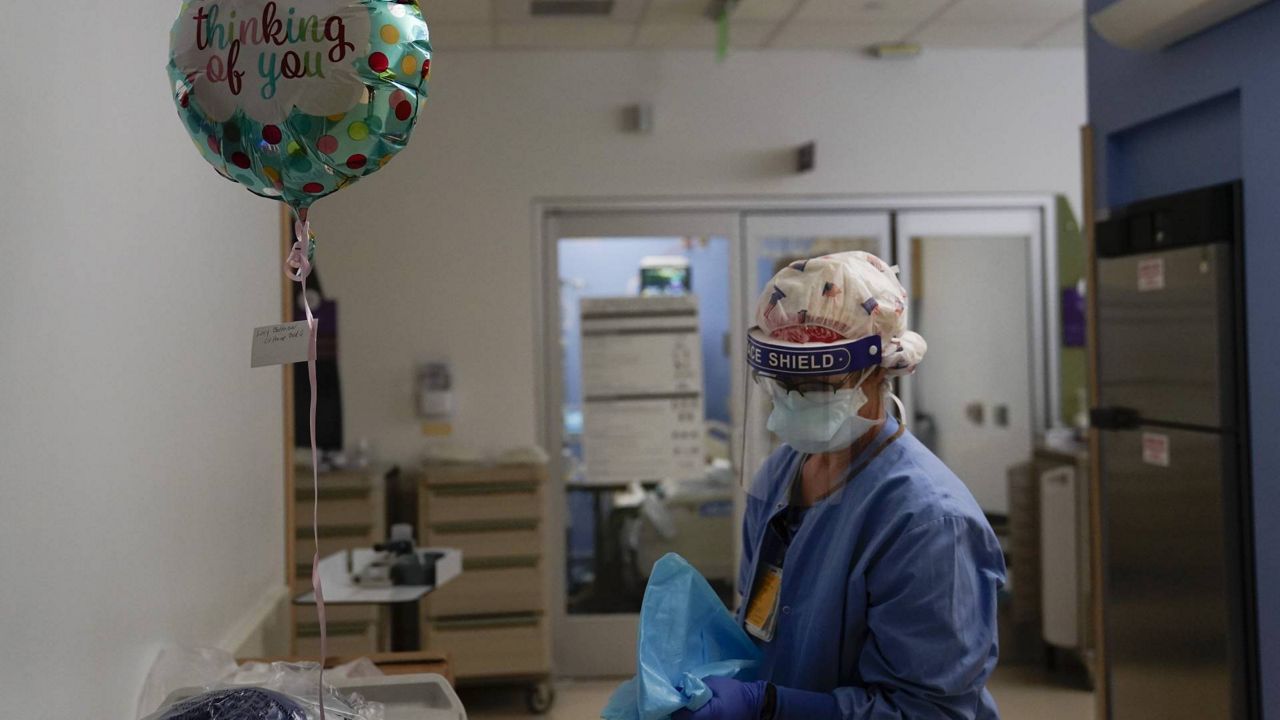 Registered nurse Anita Grohmann puts on her PPE next to a balloon delivered to a patient in a COVID-19 unit at St. Joseph Hospital in Orange, Calif., Jan. 7, 2021. (AP Photo/Jae C. Hong)