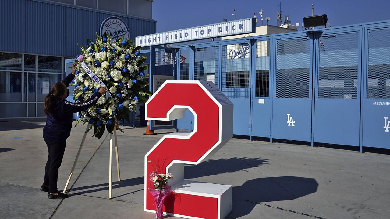 Berna Torres places a wreath in front of Tommy Lasorda's retired No. 2 at Dodger Stadium, Friday, Jan. 8, 2021, in Los Angeles.  (AP Photo/Marcio Jose Sanchez)