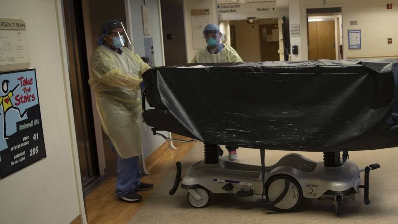 In this July 7, 2020, file photo, hospital staff members enter an elevator with the body of a COVID-19 victim on a gurney at St. Jude Medical Center in Fullerton, Calif. (AP Photo/Jae C. Hong)