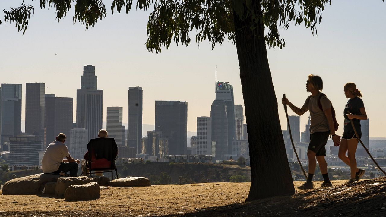 In this Jan. 11, 2021, file photo, Albert Maghbouleh, left, and Miles Santamour, 89, with Amigos de Jaibalito Foundation (ADJ) share lunch outdoors overlooking the skyline of Los Angeles. (AP Photo/Damian Dovarganes)