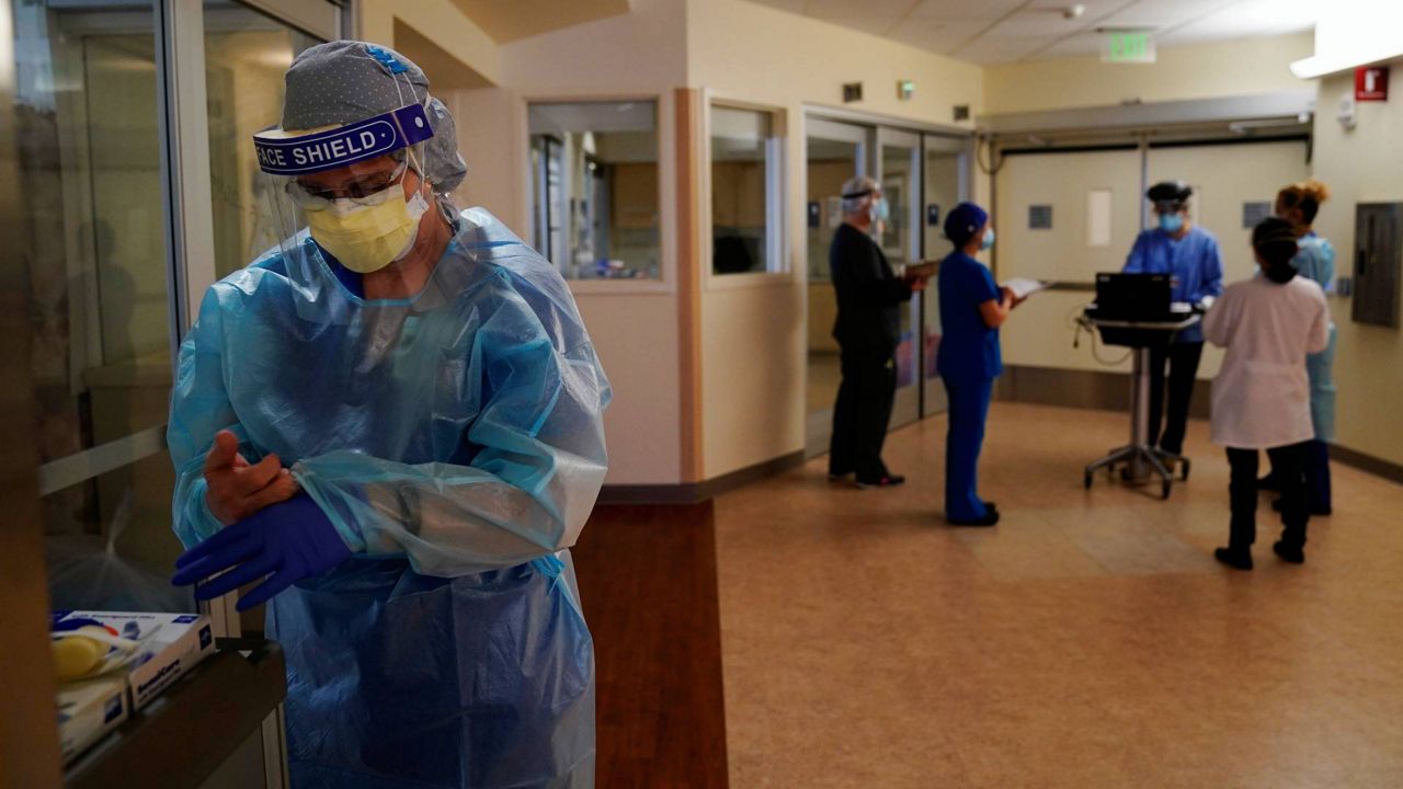 In this Jan. 7, 2021, file photo, registered nurse Merri Lynn Anderson puts on her protective equipment to check on her patient in a COVID-19 unit at St. Joseph Hospital in Orange, Calif. (AP Photo/Jae C. Hong)