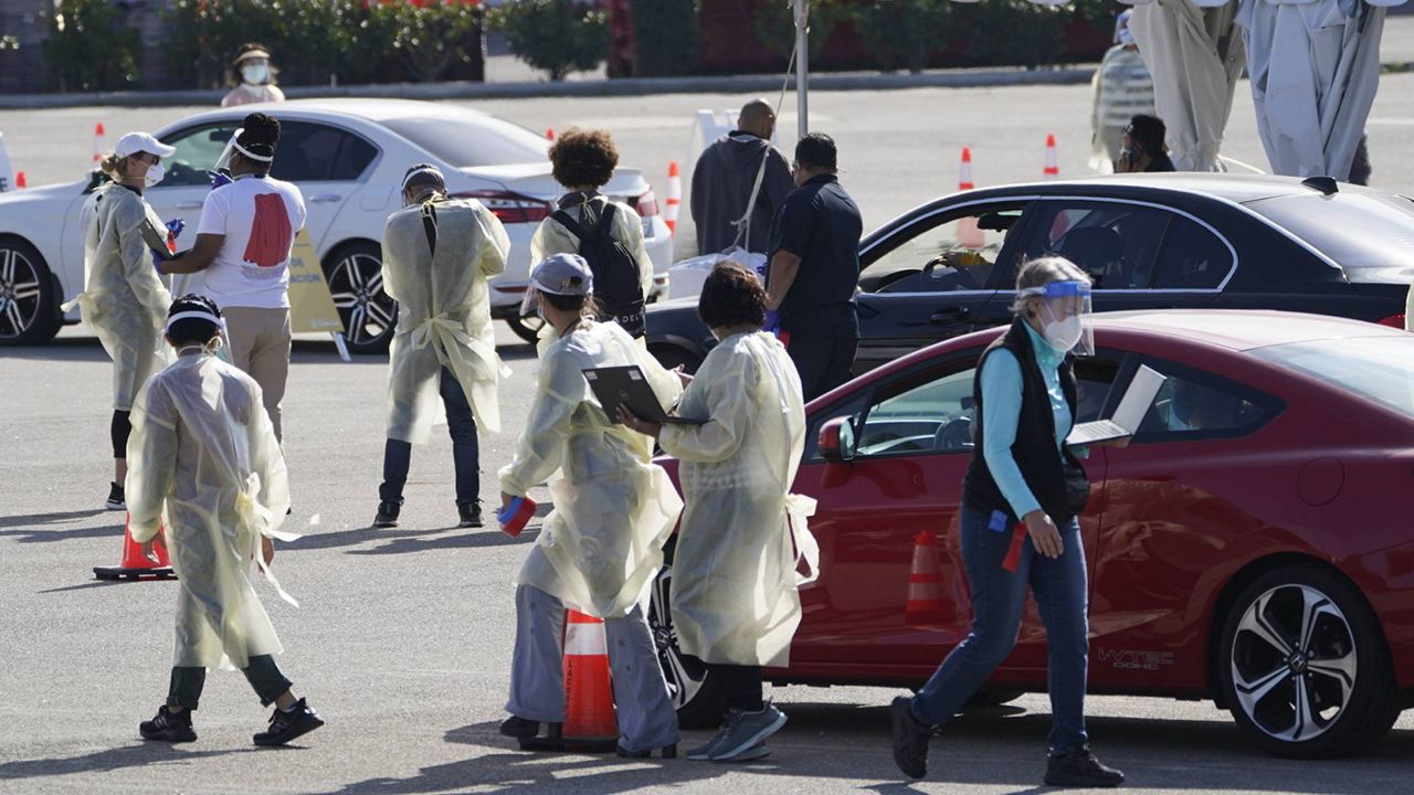 Health officials use wireless devices to register people with vaccine appointments at a mass COVID-19 vaccination site outside The Forum in Inglewood, Calif., Tuesday, Jan. 19, 2021. (AP/Damian Dovarganes)