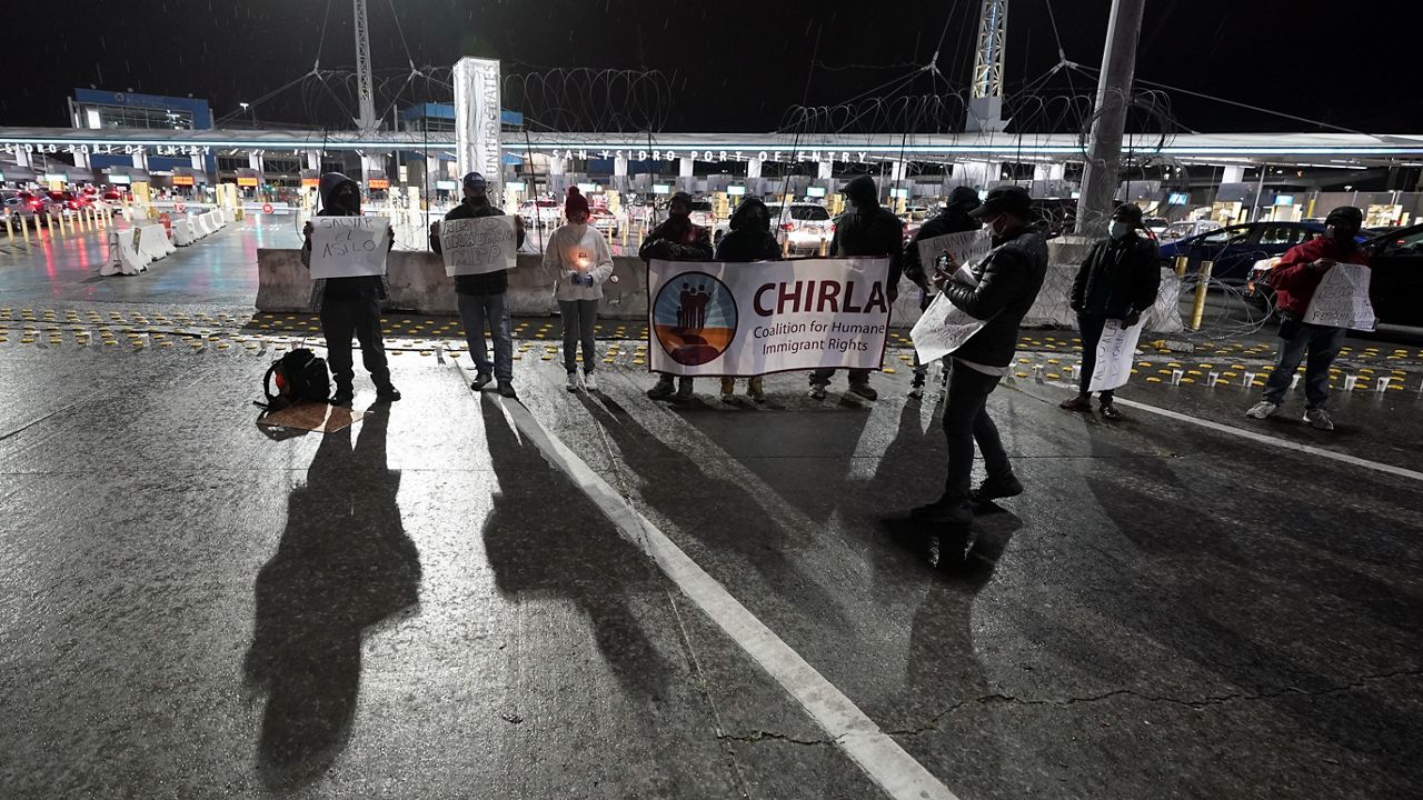 A small group stands during a vigil in support of migrants at the entrance to the San Ysidro Port of Entry along the border between the United States and Mexico, Tuesday, Jan. 19, 2021, in Tijuana, Mexico. (AP Photo/Gregory Bull)