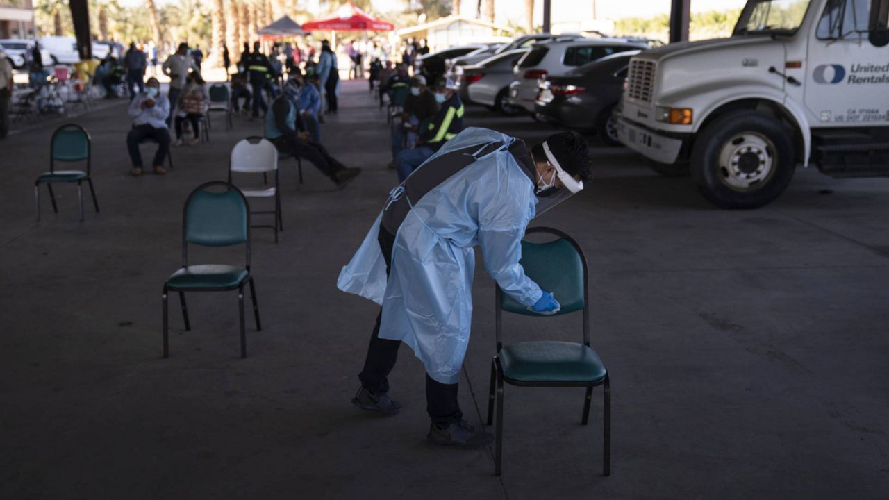 Army Reserve medic Michael Bui disinfects a chair as farm workers wait in the holding area after receiving the Pfizer-BioNTech vaccine at Tudor Ranch in Mecca, Calif., Thursday, Jan. 21, 2021. (AP Ph/Jae C. Hong)