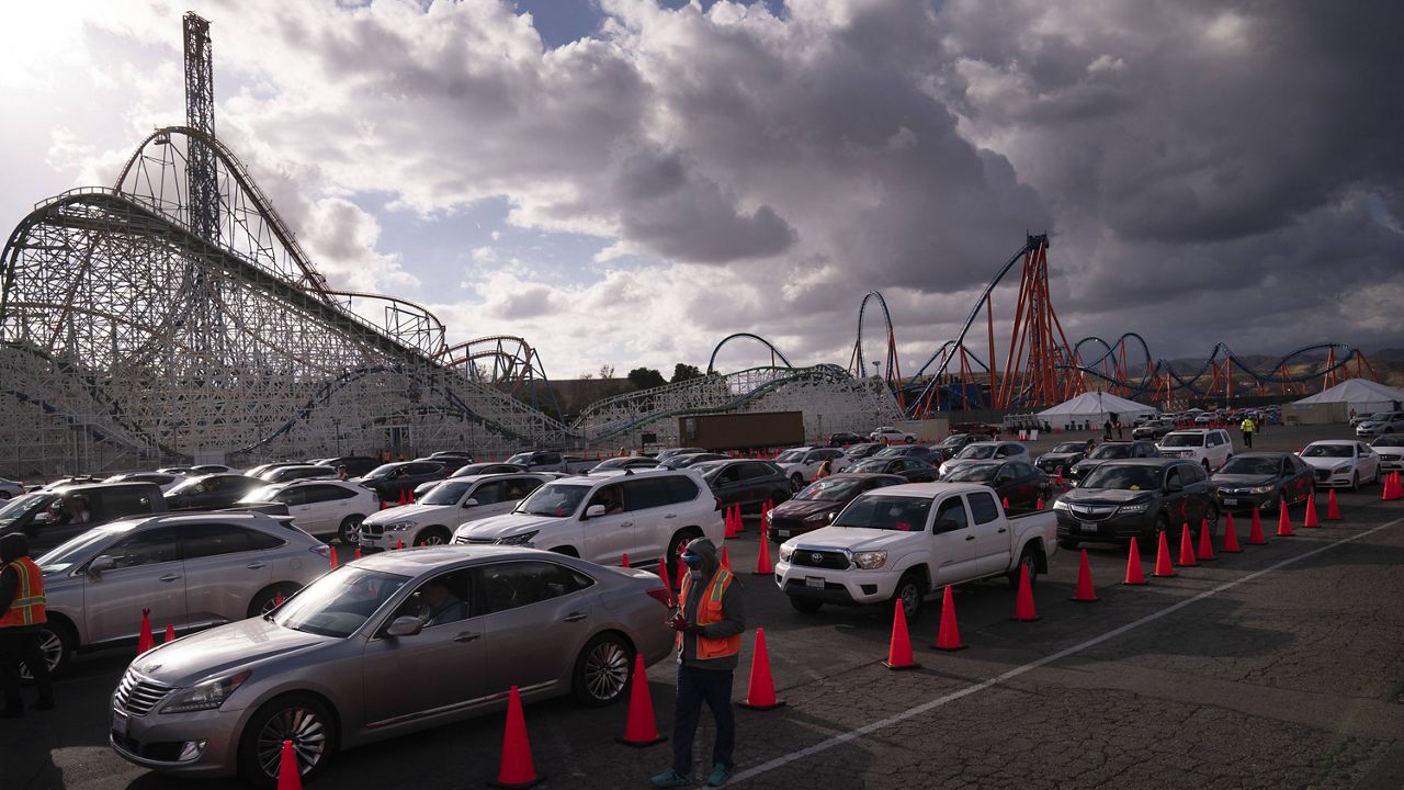 People hold in their vehicles after getting the COVID-19 vaccine at a mass vaccination site set up in the parking lot of Six Flags Magic Mountain in Valencia, Calif., Friday, Jan. 22, 2021. (AP Photo/Jae C. Hong)