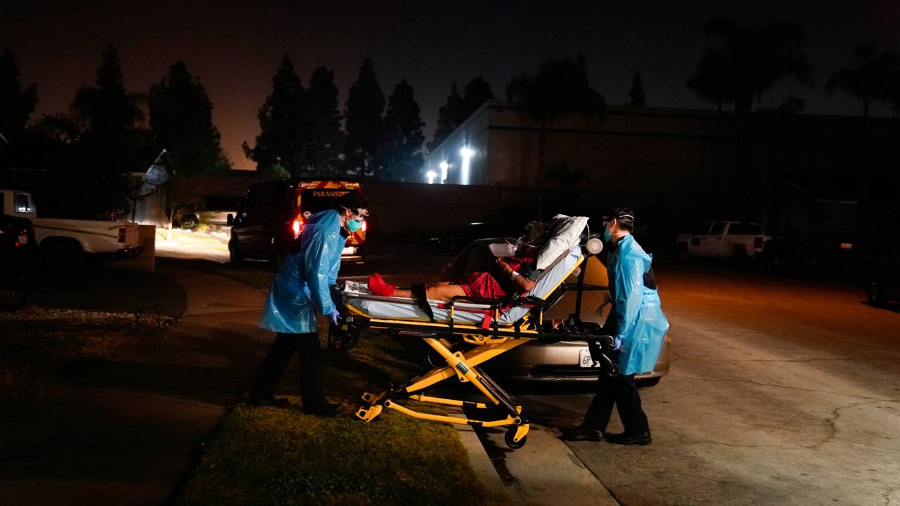 Emergency medical technicians Joshua Hammond, left, and Thomas Hoang, of Emergency Ambulance Service, transport a COVID-19 patient to an ambulance in Placentia, Calif., Jan. 8, 2021. (AP Photo/Jae C. Hong)