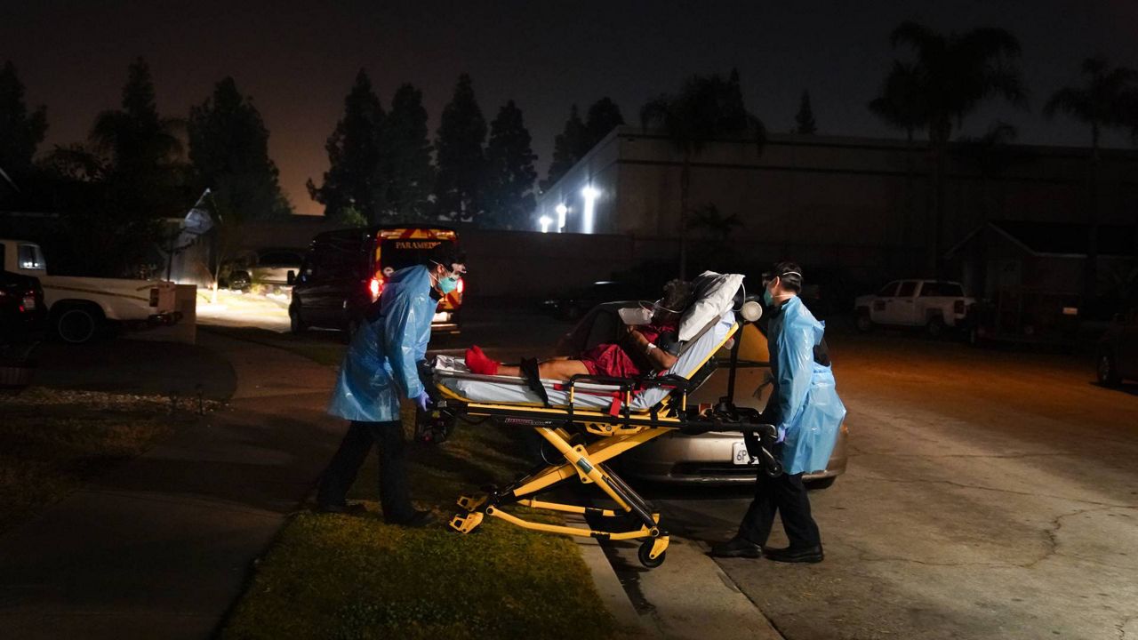 Emergency medical technicians Joshua Hammond, left, and Thomas Hoang, of Emergency Ambulance Service, transport a COVID-19 patient to an ambulance in Placentia, Calif., Jan. 8, 2021. (AP/Jae C. Hong)