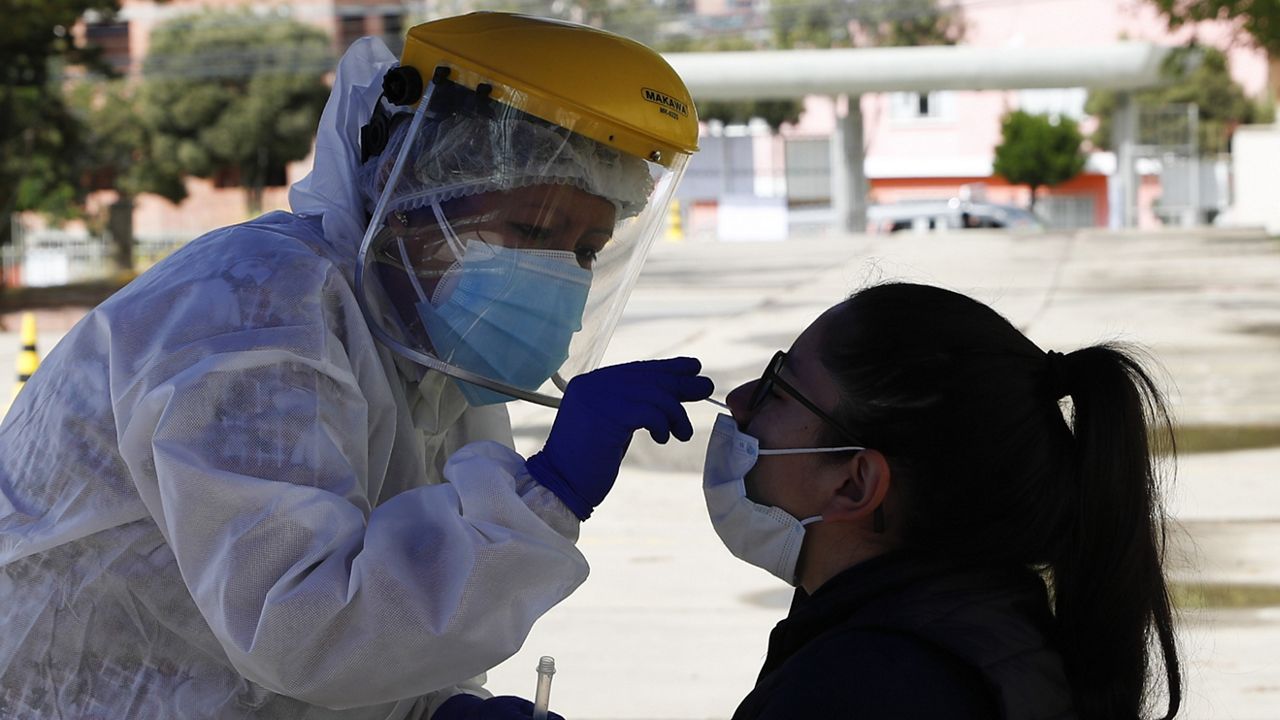 A health worker collects a sample from a resident during testing for the new coronavirus outside the Olympic Pool in La Paz, Bolivia, Tuesday, Jan. 26, 2021. (AP Photo/Juan Karita)