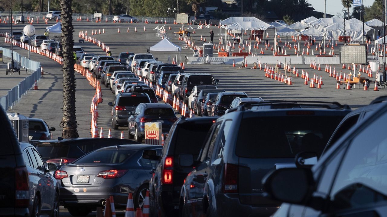 Los Angeles residents wait in line in their cars to receive a covid-19 vaccine at Dodger Stadium, Tuesday, Jan. 26, 2021. (AP Photo/Richard Vogel)
