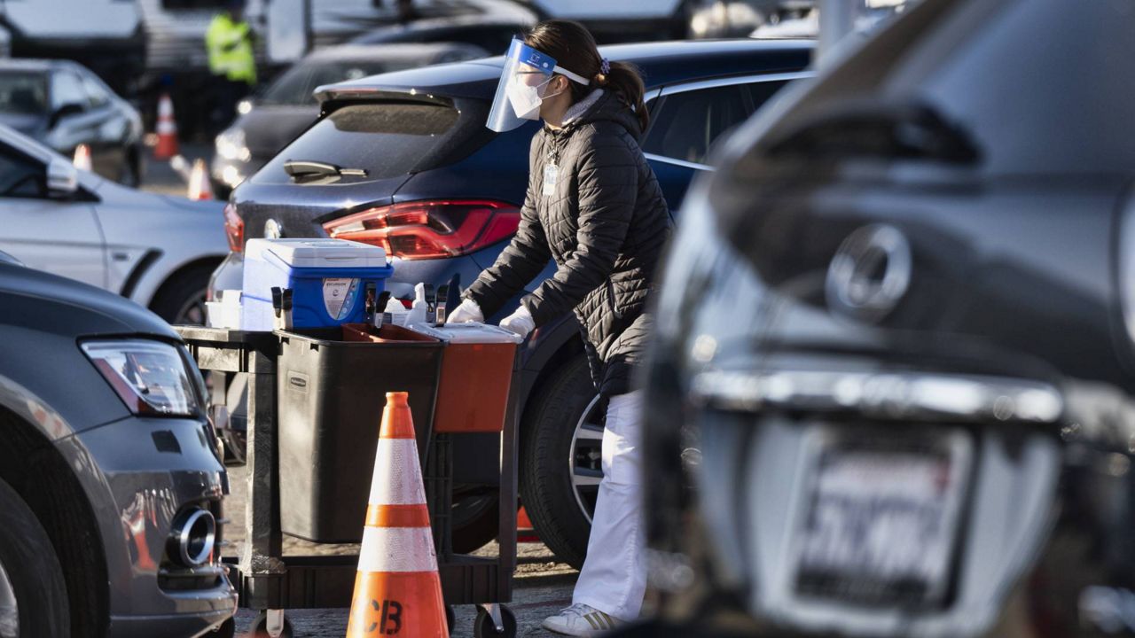 A health care worker gets ready to distribute the COVID-19 vaccine to residents waiting in their cars in the early morning at Dodger Stadium, Jan. 26, 2021, Los Angeles. (AP Photo/Richard Vogel)