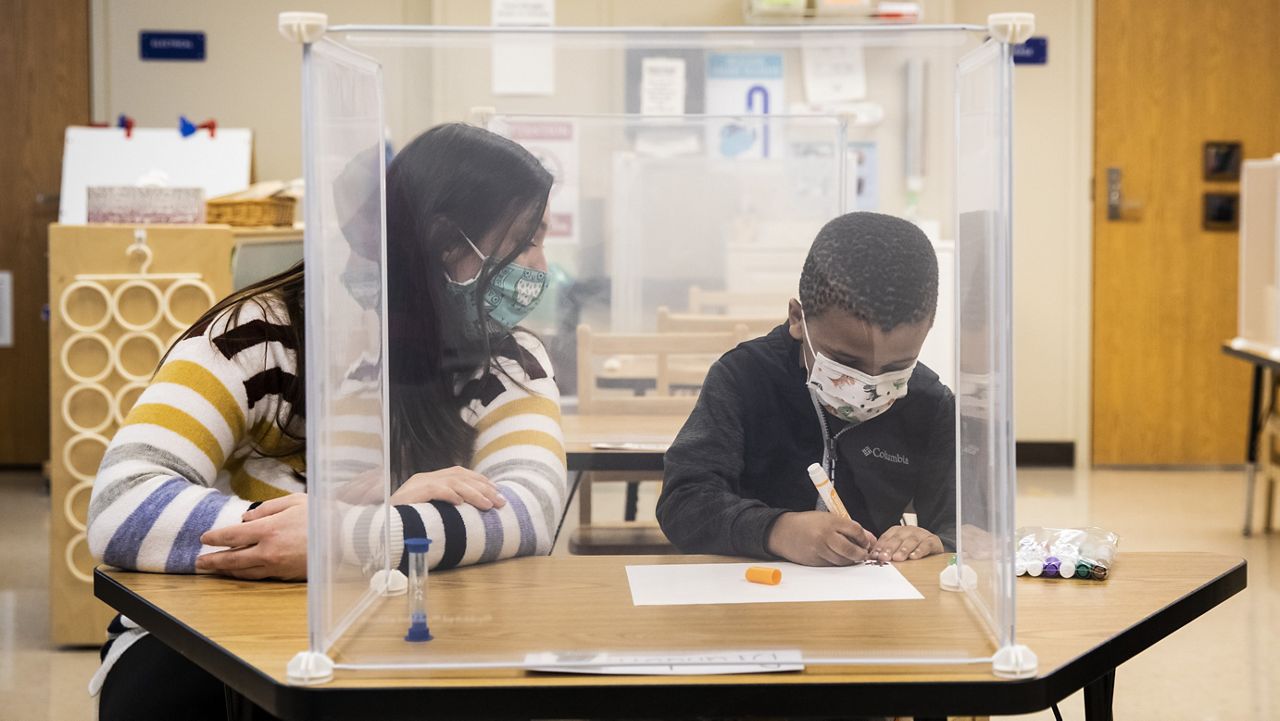 FILE - In this Jan. 11, 2021 file photo, pre-kindergarten teacher Sarah McCarthy works with a student at Dawes Elementary in Chicago. (Ashlee Rezin Garcia/Chicago Sun-Times via AP, Pool File)