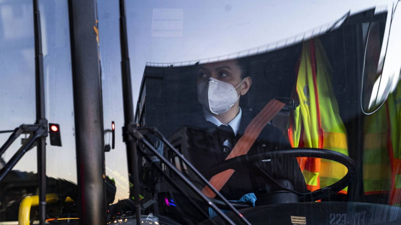 A Metro Transit bus driver wears an N95 protective mask and gloves as she drives her bus near Staples Center in downtown Los Angeles, Jan. 25, 2021. (AP Photo/Damian Dovarganes)