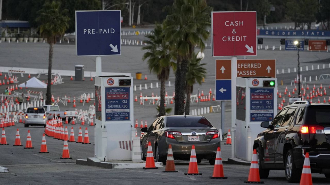 Drivers with a vaccine appointment enter a mega COVID-19 vaccination site set up in the parking lot of Dodger Stadium in Los Angeles Saturday, Jan. 30, 2021. (AP Photo/Damian Dovarganes)