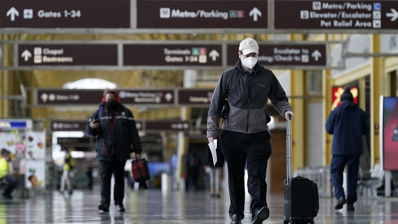 A traveler wears a face mask to protect against the spread of COVID-19 as he walks at Ronald Reagan Washington National Airport, Tuesday, Feb. 2, 2021, in Arlington, Va. (AP Photo/Patrick Semansky)