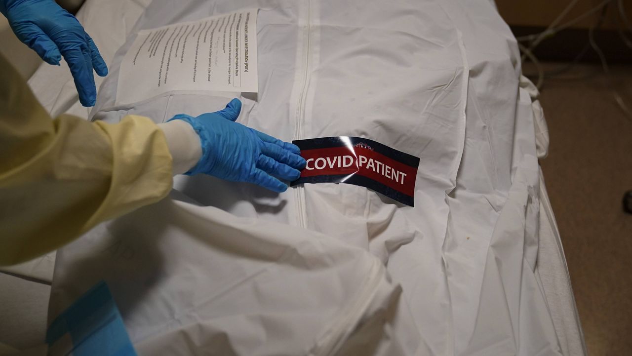 In this Jan. 9, 2021, file photo, a hospital worker places a "COVID Patient" sticker on a body bag holding a deceased patient at Providence Holy Cross Medical Center in the Mission Hills section of Los Angeles. (AP Photo/Jae C. Hong, File)