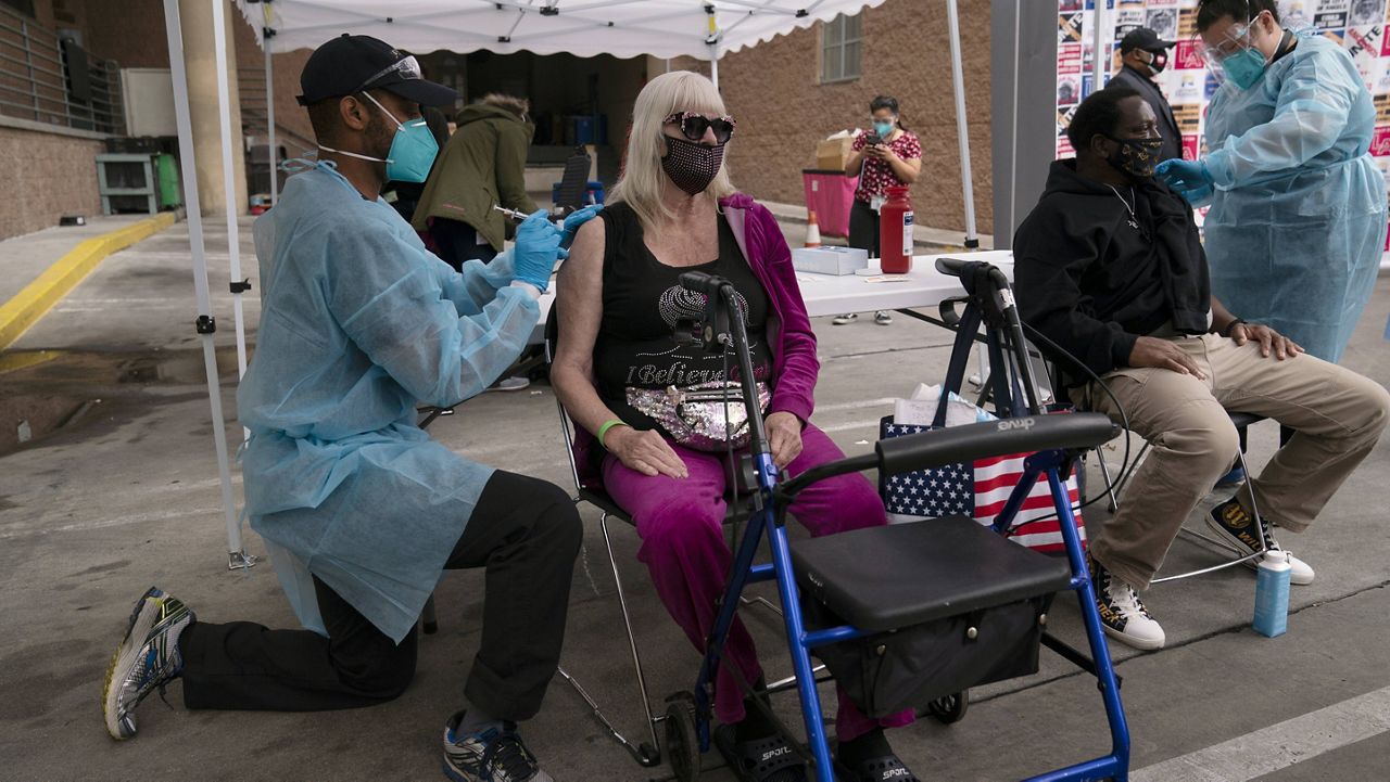 A nurse administers a COVID-19 vaccine to Connie Lach, 66, at a vaccination site set up in the parking lot of the Los Angeles Mission in the Skid Row area of Los Angeles, Wednesday, Feb. 10, 2021. (AP Photo/Jae C. Hong)