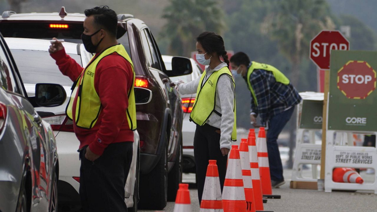 Motorists are asked about allergic pre-conditions as they line up to receive a COVID-19 vaccine at a Los Angeles County location at Dodger Stadium, Feb. 10, 2021. (AP Photo/Damian Dovarganes)