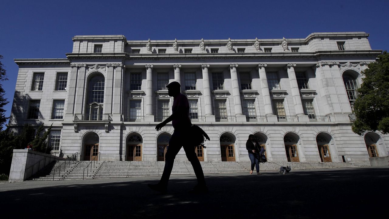 In this March 11, 2020 file photo people walk in front of Wheeler Hall on the University of California campus in Berkeley, Calif. (AP Photo/Jeff Chiu,File)
