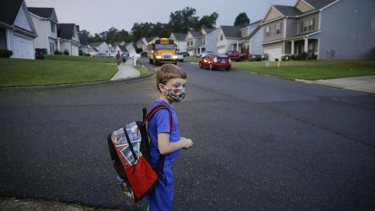 FILE - In this Aug. 3, 2020, file photo, Paul Adamus, 7, waits at the bus stop for the first day of school in Dallas, Ga. (AP Photo/Brynn Anderson, File)