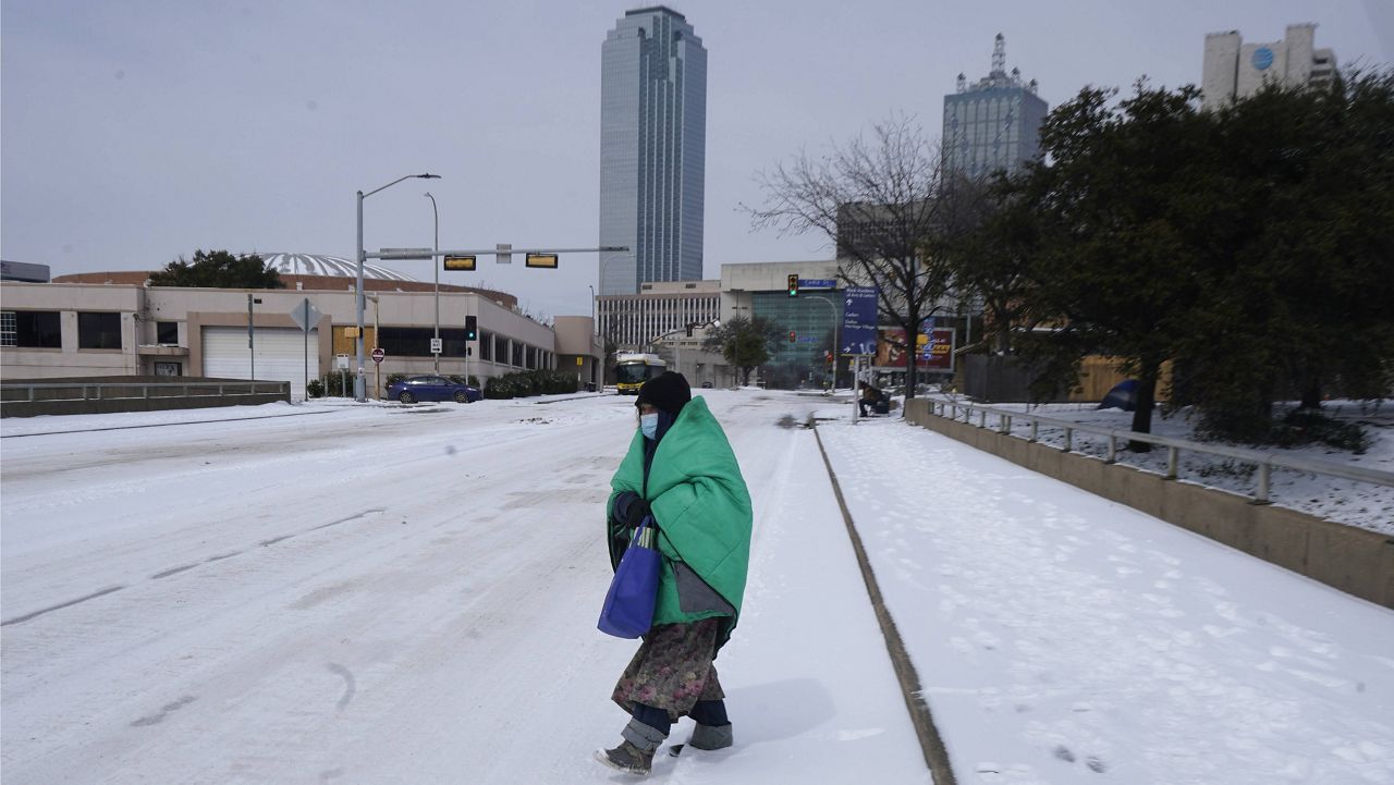 A woman wrapped in a blanket crosses the street near downtown Dallas on Tuesday. (AP Photo/LM Otero)