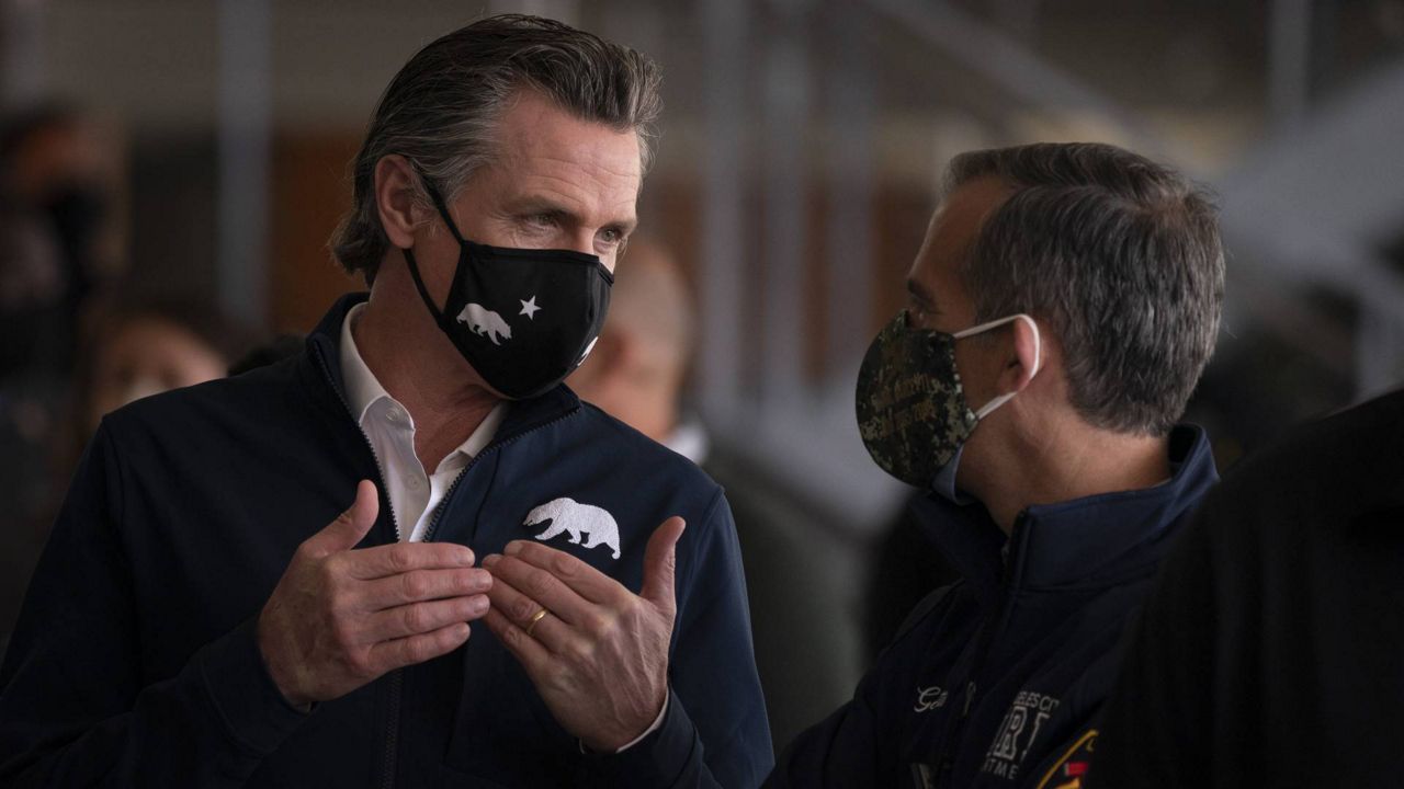 Gov. Gavin Newsom, left, talks to L.A. Mayor Eric Garcetti during a news conference at a joint state and federal COVID-19 vaccination site set up on the campus of Cal State University of L.A., Tuesday, Feb. 16, 2021. (AP/Jae C. Hong)