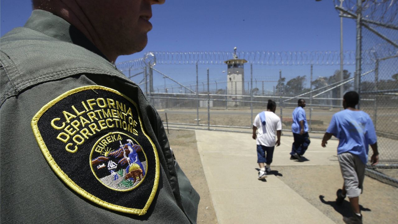 In this June 20, 2018 file photo, inmates pass a correctional officer as they leave an exercise yard at the California Medical Facility in Vacaville, Calif. (AP Photo/Rich Pedroncelli, File)