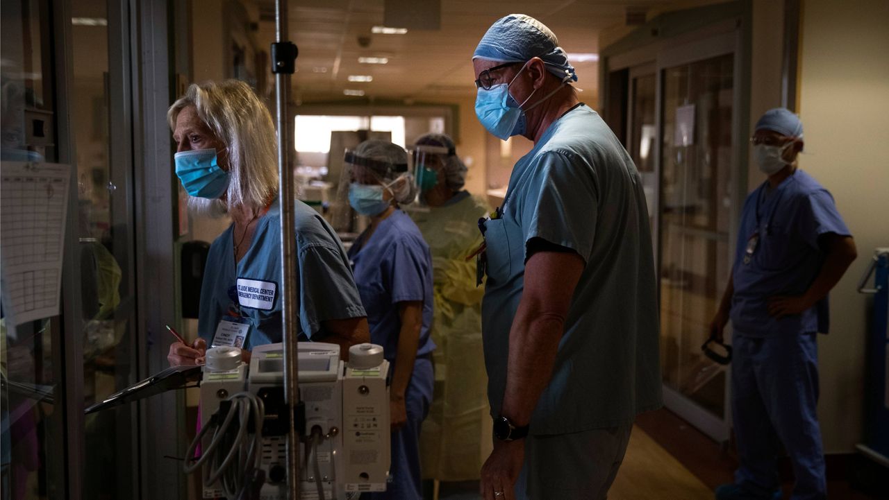 Nurse Cindy Kelbert, left, checks on a critically ill COVID-19 patient through a glass door as she is surrounded by other nurses at St. Jude Medical Center in Fullerton, Calif. (AP Photo/Jae C. Hong, File)