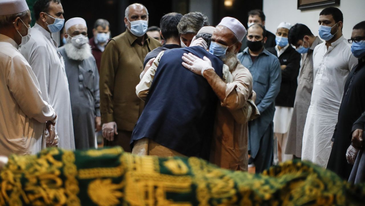 FILE - In this May 17, 2020, file photo, Mohammad Ayaz, cousin of Mohammad Altaf, center right, is hugged by a mourner after funeral prayers are given over Altaf's body at Al-Rayaan Muslim Funeral Services in the Brooklyn borough of New York. (AP Photo/John Minchillo)