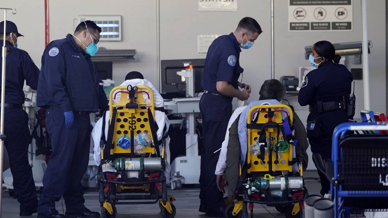 L.A. County emergency medical technicians deliver patients for admission at the Ambulatory Care Center station at the MLK Community Medical Group hospital in L.A., Feb. 24, 2021. (AP/Damian Dovarganes)