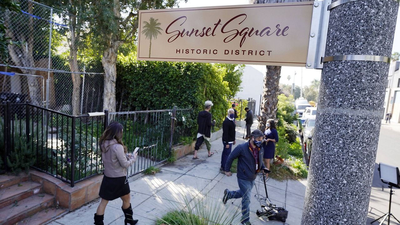 Members of the media and neighbors walk near an area on North Sierra Bonita Ave. where Lady Gaga's dog walker was shot and two of her French bulldogs stolen, Thursday, Feb. 25, 2021, in Los Angeles. The dog walker was shot once Wednesday night and is expected to survive his injuries. The man was walking three of Lady Gaga's dogs at the time but one escaped. (AP Photo/Chris Pizzello)