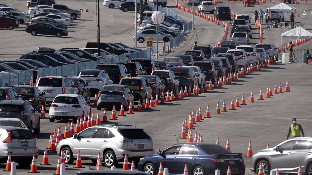 Cars wait in line as they enter a COVID-19 vaccination site at Dodger Stadium in Los Angeles, on Thursday, Feb. 25, 2021. (AP Photo/Richard Vogel)