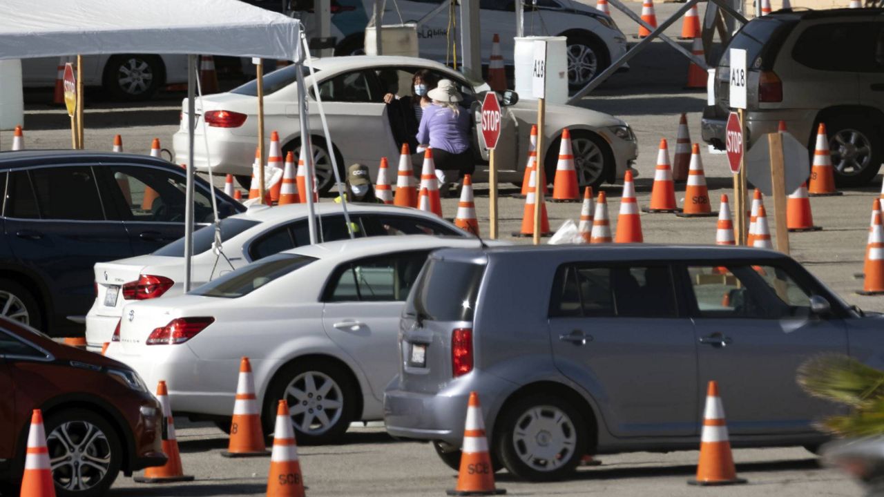 A woman gets inoculated in her car with the Moderna COVID-19 vaccine in the Dodger Stadium parking lot in Los Angeles, on Thursday, Feb. 25, 2021. (AP Photo/Richard Vogel)