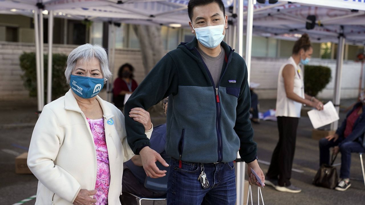 Hoa Pham, left, walks with her grandson Daniel Tran after receiving her second dose of Pfizer's COVID-19 vaccine at Families Together of Orange County Community Health Center, Friday, Feb. 26, 2021, in Tustin, Calif. (AP Photo/Marcio Jose Sanchez)