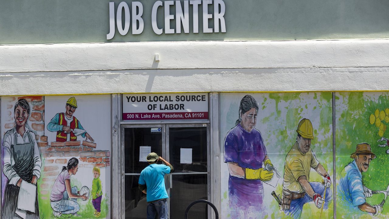 In this May 7, 2020, file photo, a person looks inside the closed doors of the Pasadena Community Job Center in Pasadena, Calif. (AP Photo/Damian Dovarganes, File)