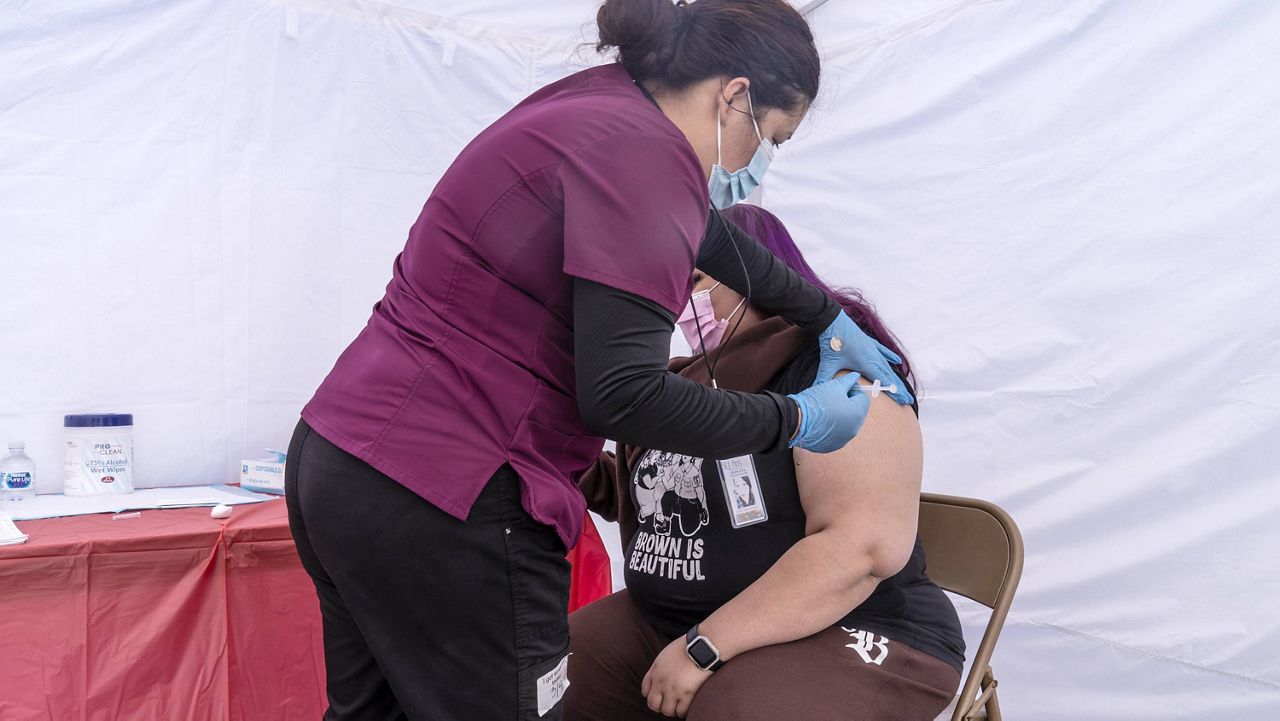 Joana Luna, a temporary medical assistant, left, inoculates Carmen Jimenez, 35, a resident of ZIP code 90001, at the St. John's Well Child and Family Center's COVID-19 vaccination site at the East Los Angeles Civic Center in Los Angeles, Thursday, March 4, 2021. (AP Photo/Damian Dovarganes)