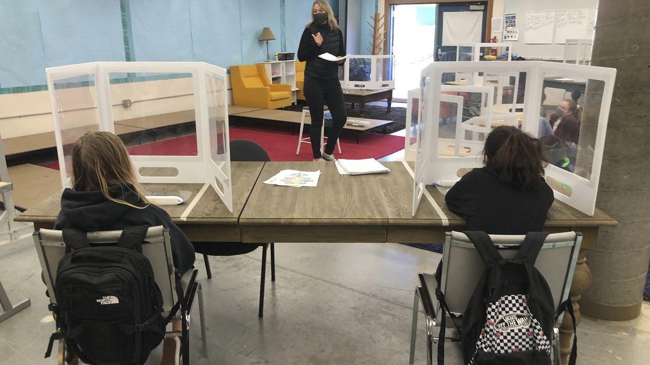 FILE - In this March 2, 2021, file photo, science teacher Jennifer Becker, center, at the Sinaloa Middle School talks to her students who are distanced at their desks in Novato, Calif. (AP Photo/Haven Daley, File)