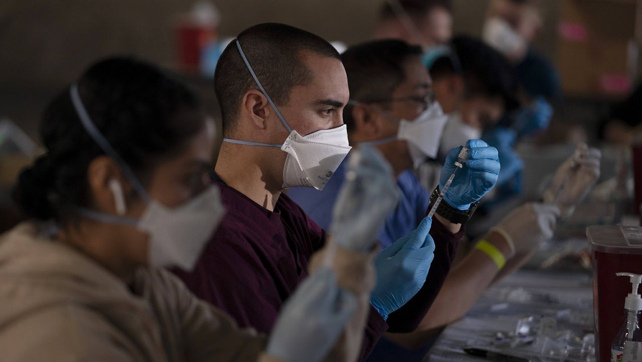 Members of the National Guard fill syringes with Pfizer's COVID-19 vaccine at a vaccination site in Long Beach, Calif., Friday, March 5, 2021. (AP Photo/Jae C. Hong)