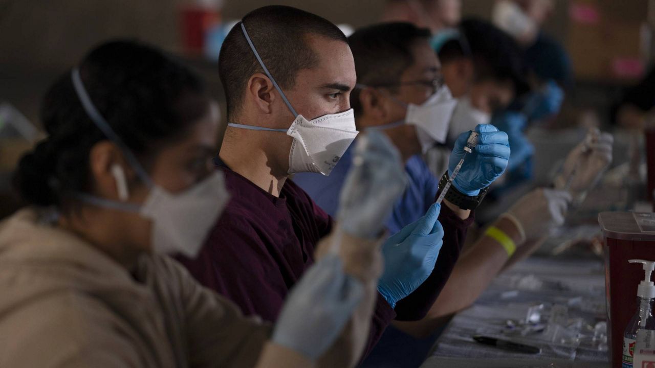Members of the National Guard fill syringes with Pfizer's COVID-19 vaccine at a vaccination site in Long Beach, Calif., Friday, March 5, 2021. (AP Photo/Jae C. Hong)