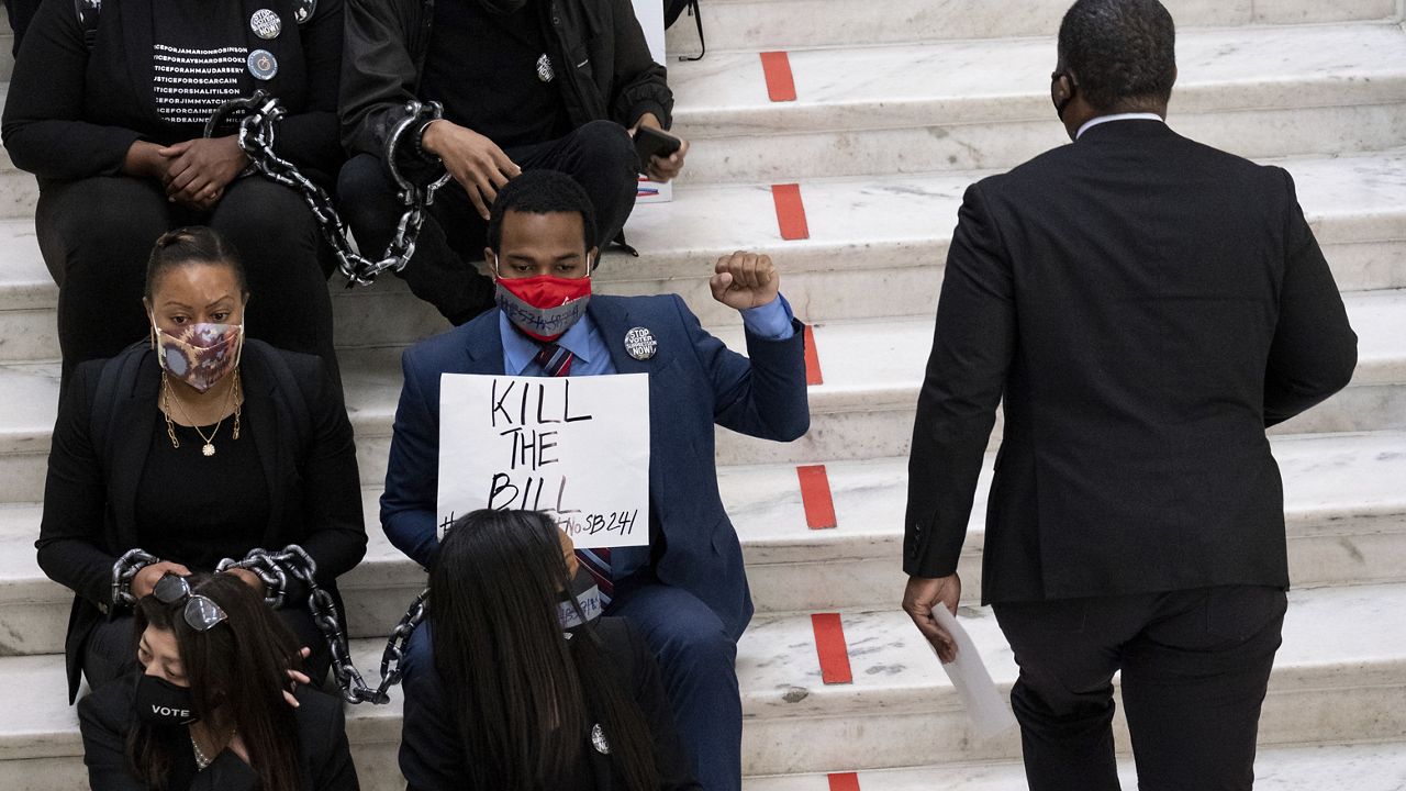 Protesters opposed to changes in Georgia's voting laws sit on the steps inside the State Capitol in Atlanta, Ga., as the Legislature meets Monday, March 8, 2021, in Atlanta. (AP Photo/Ben Gray)