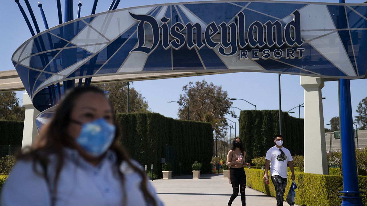 A woman with a mask waits to cross the street outside Disneyland Resort in Anaheim, Calif., Tuesday, March 9, 2021. (AP Photo/Jae C. Hong)