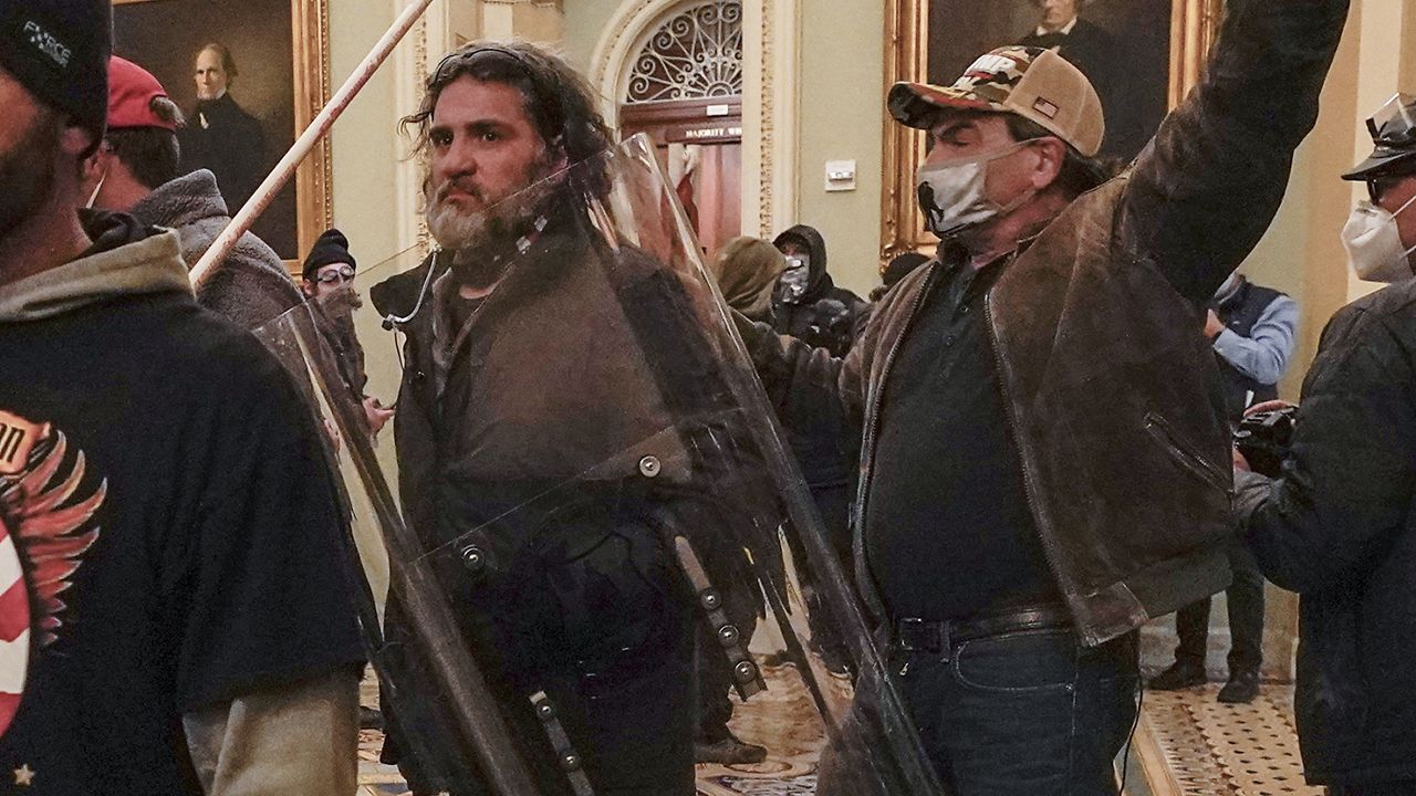 In this Jan. 6, 2021, photo, rioters, including Dominic Pezzola, center with police shield, are confronted by U.S. Capitol Police officers outside the Senate Chamber inside the Capitol, Wednesday, Jan. 6, 2021, in Washington. The Proud Boys and Oath Keepers make up a fraction of the more than 300 Trump supporters charged so far in the siege that led to Trump's second impeachment and resulted in the deaths of five people, including a police officer. But several of their leaders, members and associates have become the central targets of the Justice Department’s sprawling investigation. (AP Photo/Manuel Balce Ceneta)