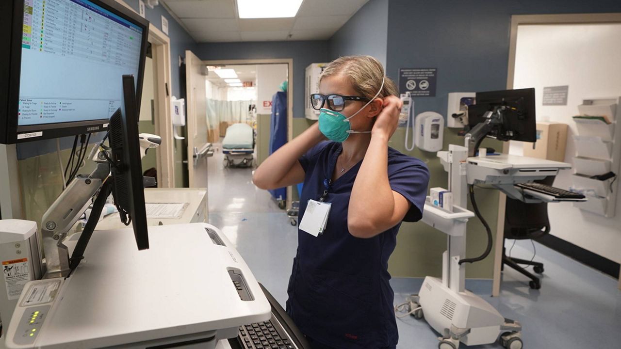 Registered nurse Sandra Younan adjusts her N95 face mask as she checks her patients’ records at Providence Cedars-Sinai Tarzana Medical Center in the Tarzana neighborhood of L.A. on March 11, 2021. (AP Photo/Damian Dovarganes)