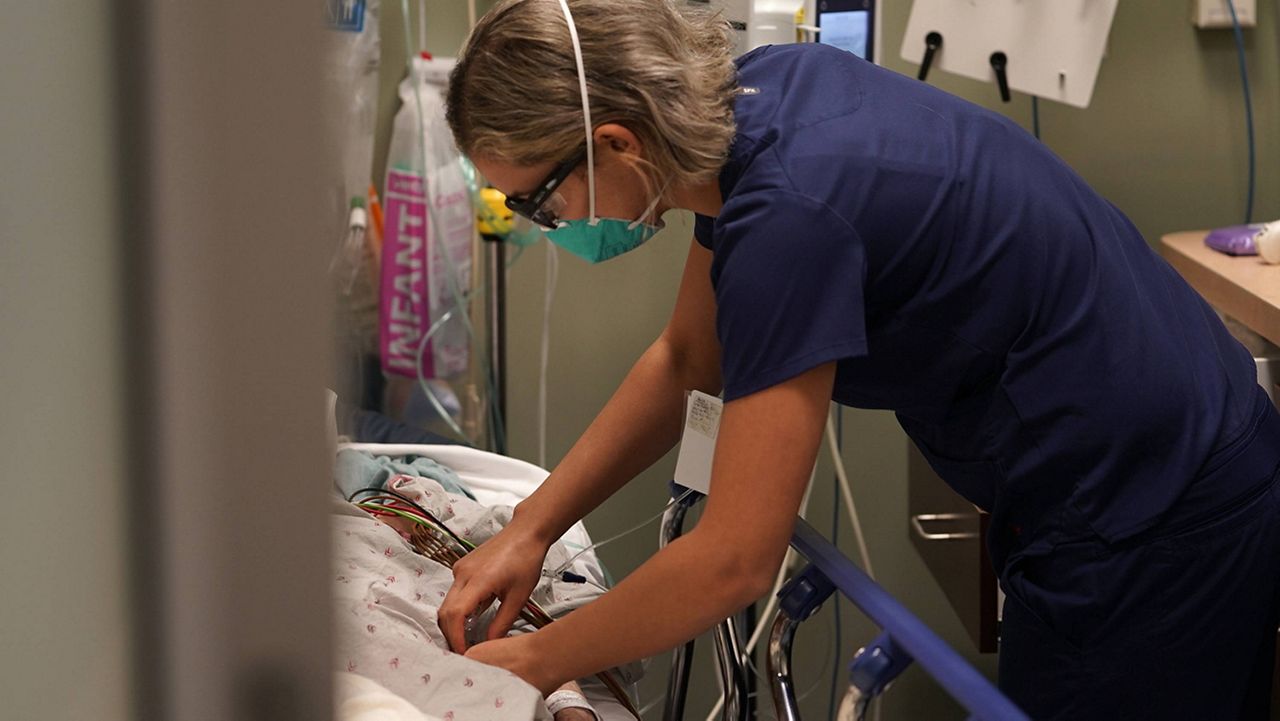 Registered nurse Sandra Younan adjusts an intravenous line for a patient at the emergency room of Providence Cedars-Sinai Tarzana Medical Center in the Tarzana neighborhood of Los Angeles on Thursday, March 11, 2021. (AP Photo/Damian Dovarganes)