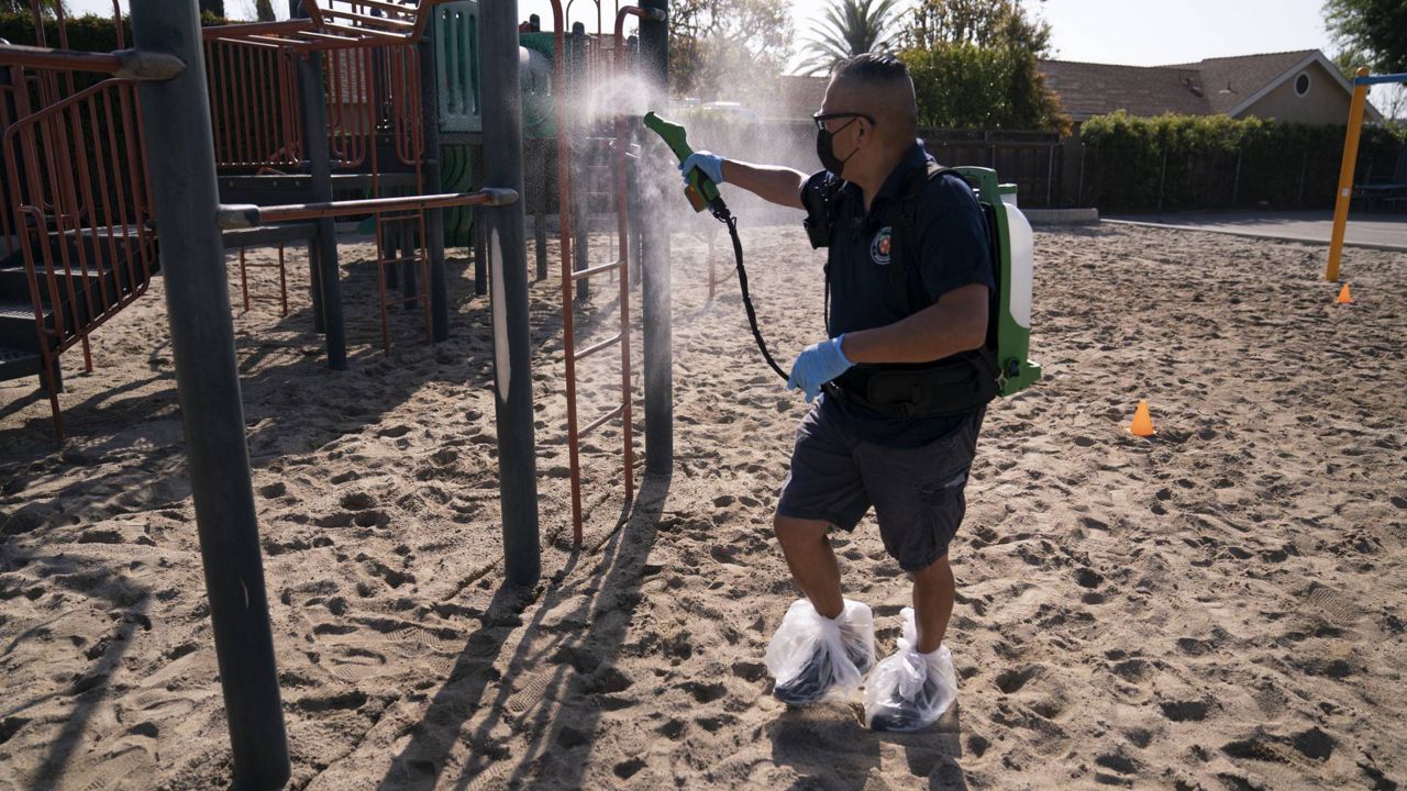 Custodian Jesse Murillo disinfects playground equipment at West Orange Elementary School in Orange, Calif., Thursday, March 18, 2021. (AP Photo/Jae C. Hong)