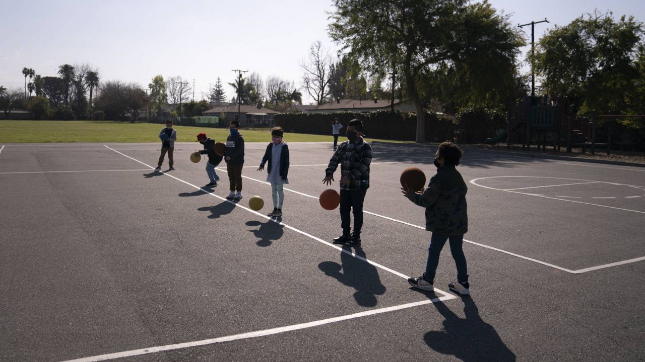 Socially distanced students wait for their turns to shoot on a basketball court at West Orange Elementary School in Orange, Calif., March 18, 2021. (AP Photo/Jae C. Hong)
