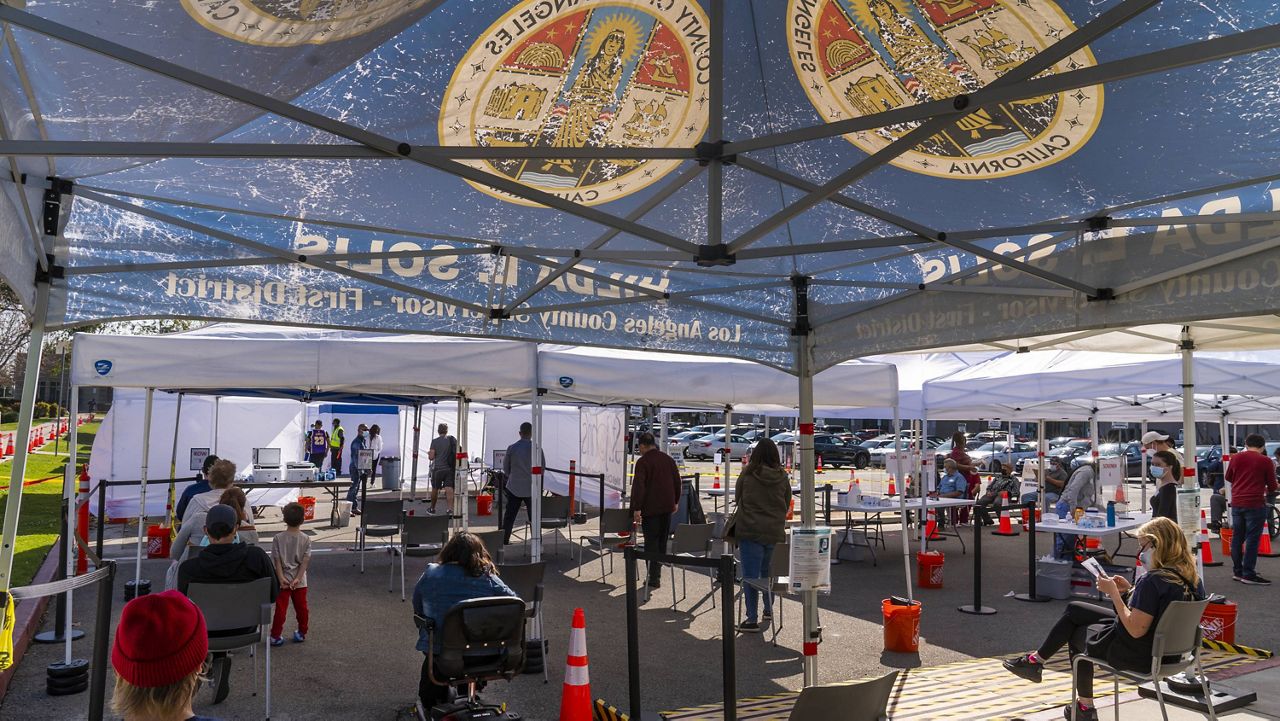 In this March 4, 2021 file photo, people wait under tents for their turn to be vaccinated at the St. John's Well Child and Family Center COVID-19 vaccination site at the East Los Angeles Civic Center in Los Angeles. (AP Photo/Rick Scuteri)