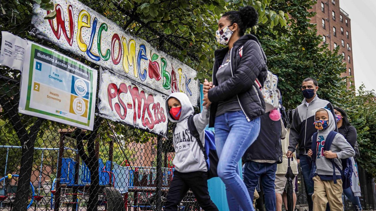 Students arrive with their guardians for in-person classes at Public School 188 in New York. New York City public school students will get another chance to go back to school in-person this spring after federal authorities eased their guidance on how many children can safely fit in a classroom.