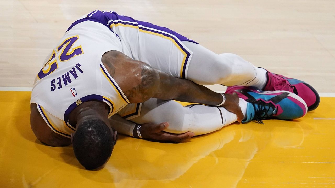 Lakers forward LeBron James holds his ankle after going down with an injury during the first half of an NBA game against the Atlanta Hawks Saturday, March 20, 2021, in Los Angeles. (AP Photo/Marcio Jose Sanchez)