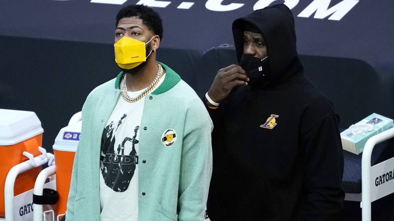 Lakers forwards Anthony Davis and LeBron James watch from the sideline during an NBA game against the Phoenix Suns, Sunday, March 21, 2021, in Phoenix. (AP Photo/Rick Scuteri)